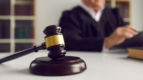 Close-up of wooden gavel placed on sound block on judge's table during court hearing