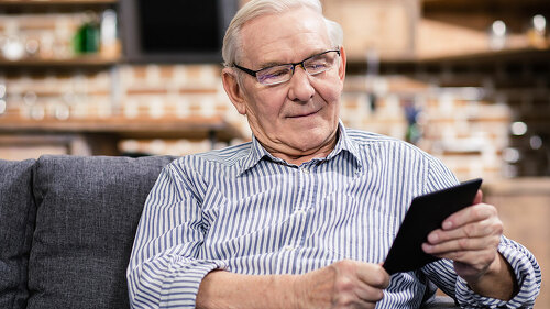 Pleasant aged man reading an e book