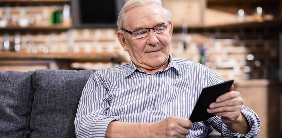 Pleasant aged man reading an e book