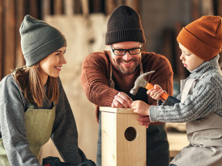 Kid with parents assembling wooden bird house in craft workshop