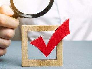 A man examines a red check mark through a magnifying glass. Assessing the transparency of the legitimacy of an election or referendum. Illegal Anex, falsifications and violations. Democracy.
