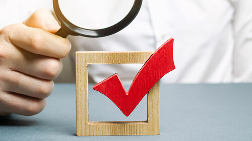 A man examines a red check mark through a magnifying glass. Assessing the transparency of the legitimacy of an election or referendum. Illegal Anex, falsifications and violations. Democracy.