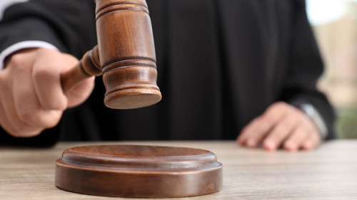 Judge with gavel at wooden table indoors, closeup. Criminal law