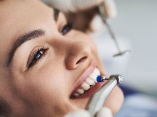Charming young lady receiving teeth cleaning and polishing at clinic