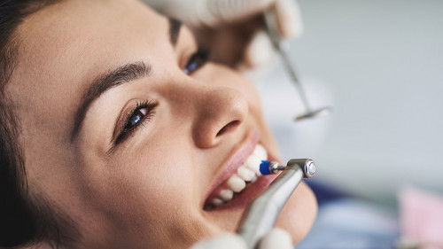 Charming young lady receiving teeth cleaning and polishing at clinic