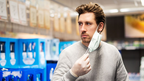 Coronavirus, Mann schützt sich im Laden mit Atemmaske und Hands