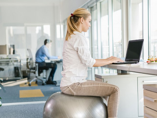 Business woman working on laptop in office while sitting on pila