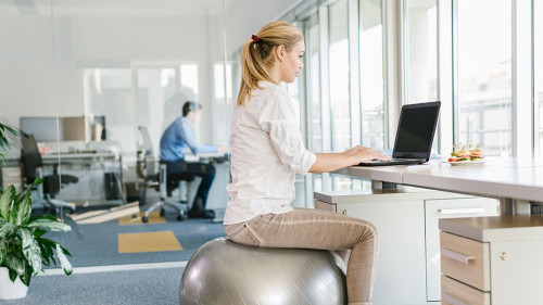 Business woman working on laptop in office while sitting on pila