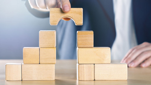 Business man bridging the gap between two towers or parties made