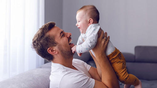 Playful handsome caucasian young dad lifting his loving 6 months