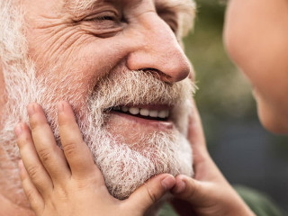 Old smiling man and his granddaughter looking each other