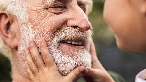 Old smiling man and his granddaughter looking each other