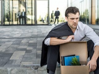 Fired businessman sitting on street