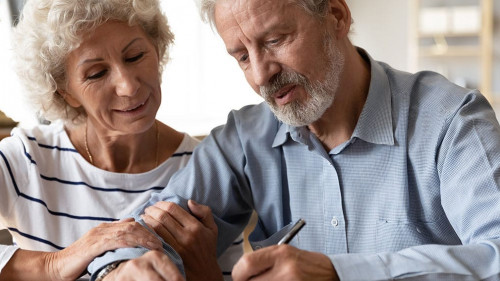 Happy senior couple signing legal documents, making purchasing deal
