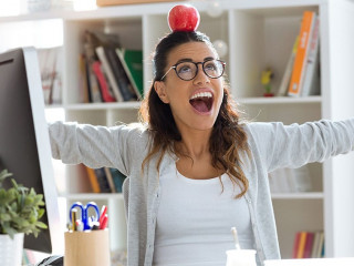 Happy young business woman having fun and holding red apple over