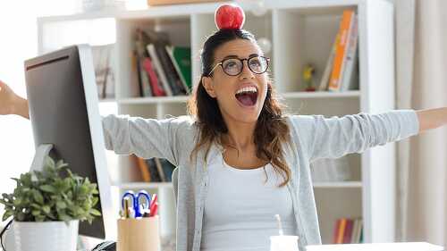 Happy young business woman having fun and holding red apple over