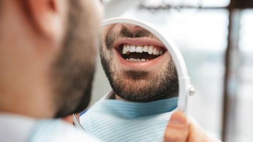 Handsome happy young man sitting in medical dentist center.