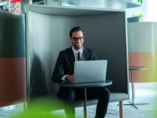 Smiling successful manager dressed in formal wear using laptop a