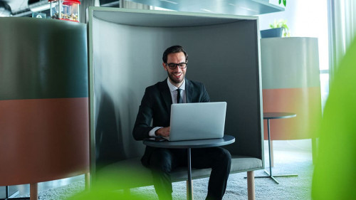 Smiling successful manager dressed in formal wear using laptop a