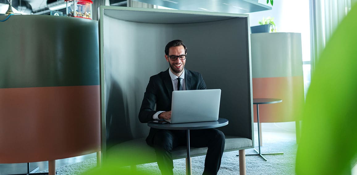 Smiling successful manager dressed in formal wear using laptop a
