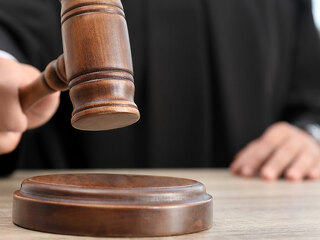 Judge with gavel at wooden table indoors, closeup. Criminal law