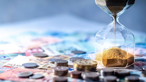 Hourglass and currency on table, Time Investment concept