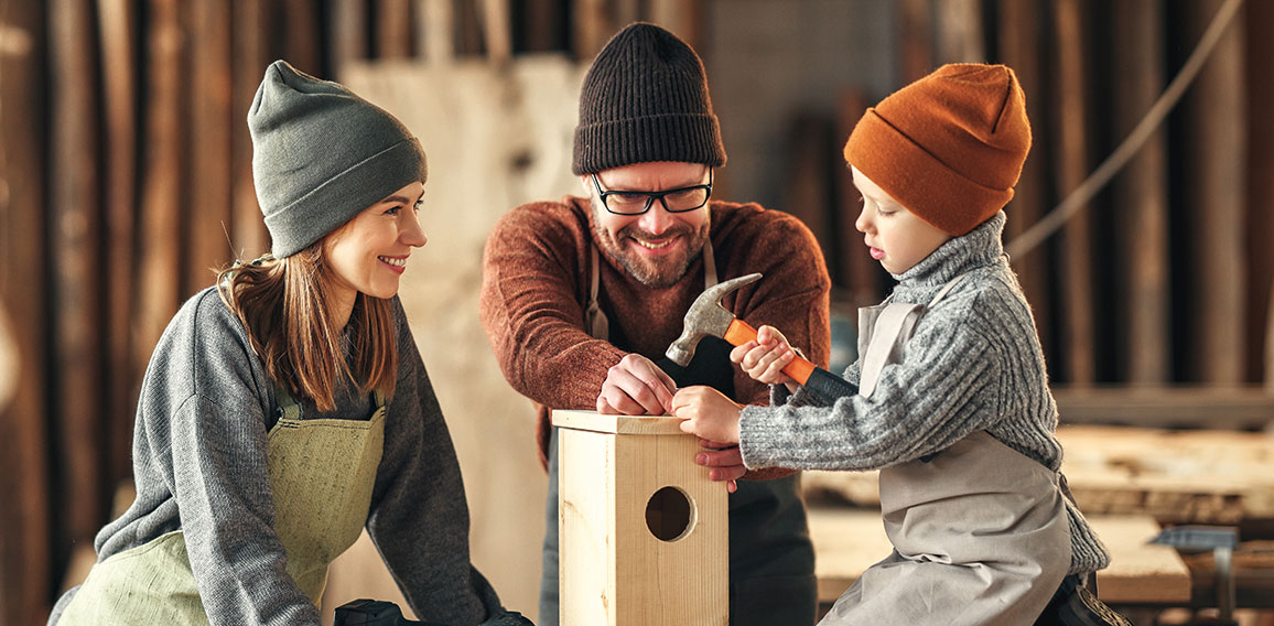 Kid with parents assembling wooden bird house in craft workshop