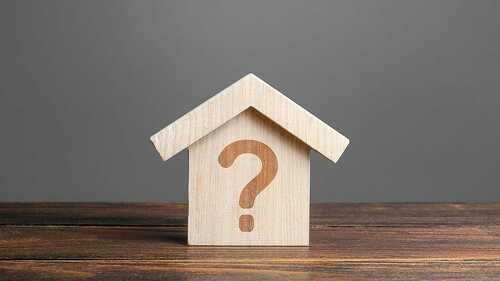 Question mark on a wooden house. Solving housing problems, deciding to buy or rent real estate. Search for options, the choice of accommodation between apartment and house. Cost estimate