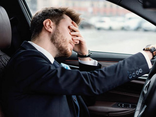 Sad young businessman driving alone in his new car