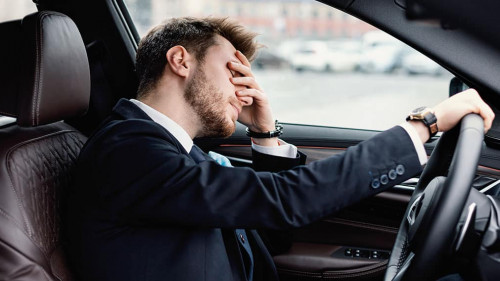 Sad young businessman driving alone in his new car
