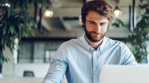 Businessman in shirt working on his laptop in an office