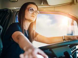 Portrait of beautiful young woman professional truck driver sitt
