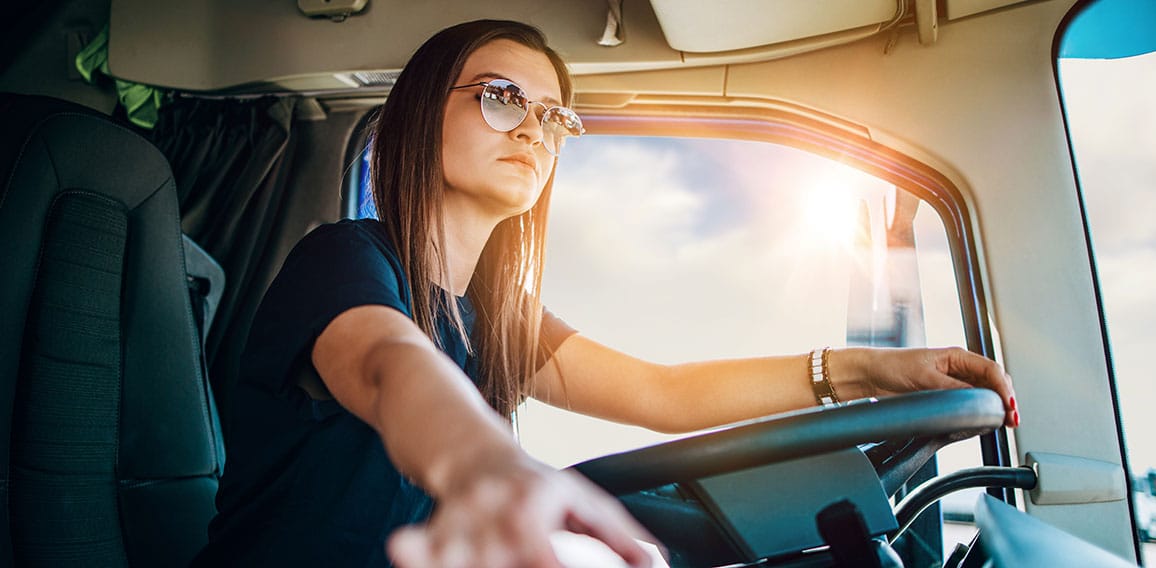 Portrait of beautiful young woman professional truck driver sitt