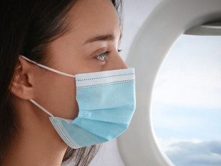 Traveling by airplane during coronavirus pandemic. Woman with fa