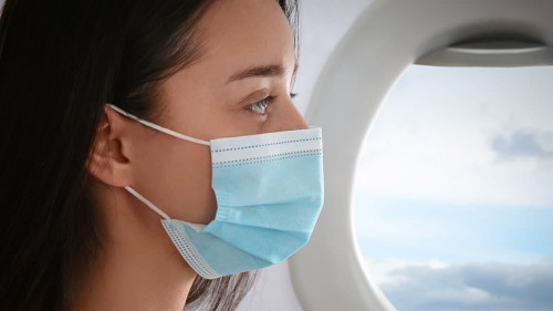 Traveling by airplane during coronavirus pandemic. Woman with fa