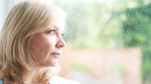 Sad Mature Woman Suffering From Agoraphobia Looking Out Of Windo