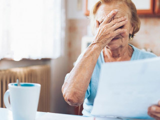 Elderly woman looking at her utility bills