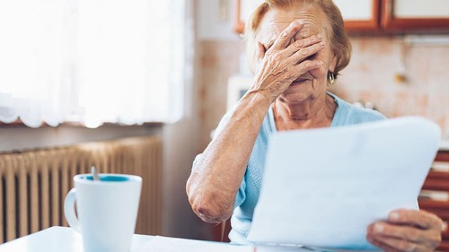 Elderly woman looking at her utility bills
