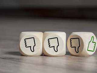 Cubes dice with thumbs up and down on wooden background