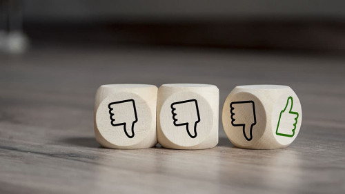 Cubes dice with thumbs up and down on wooden background