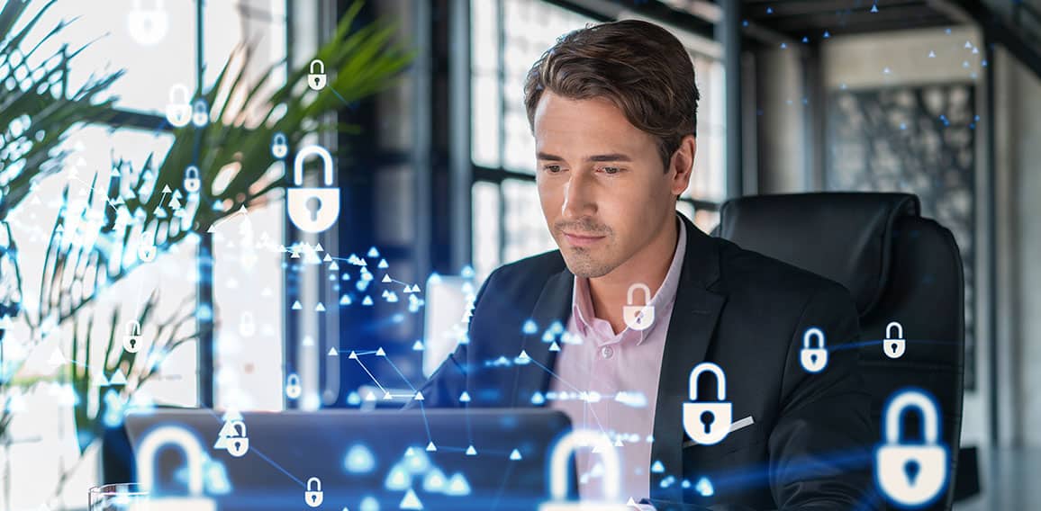 Handsome businessman in suit at workplace working with laptop to defend customer cyber security. Concept of clients information protection and brainstorm. Padlock hologram over office background.