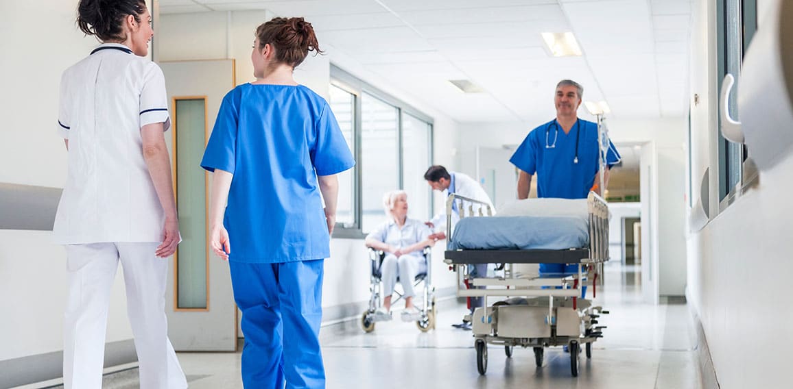 Male nurse pushing stretcher gurney bed in hospital corridor wit