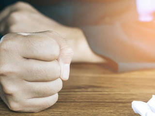 angry business man hand with crumpled paper on table , feeling
