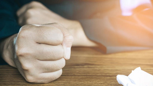 angry business man hand with crumpled paper on table , feeling