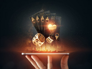 Creative background, online casino, in a man's hand a smartphone with playing cards, roulette and chips, black-gold background. Internet gambling concept. Copy space