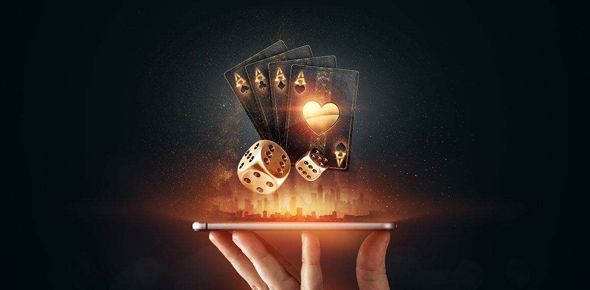 Creative background, online casino, in a man's hand a smartphone with playing cards, roulette and chips, black-gold background. Internet gambling concept. Copy space