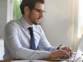 Attractive businessman typing on laptop in modern office