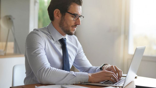 Attractive businessman typing on laptop in modern office