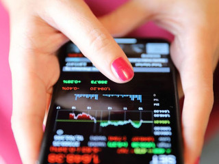 Female hand with smartphone trading stock online in coffee shop