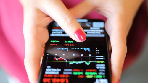 Female hand with smartphone trading stock online in coffee shop